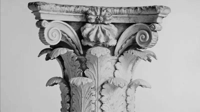 Weathered Corinthian capital photographed against a pale wall