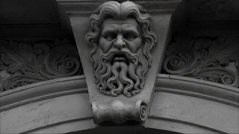 Bearded stone face carved on an arch keystone between acanthus scrolls