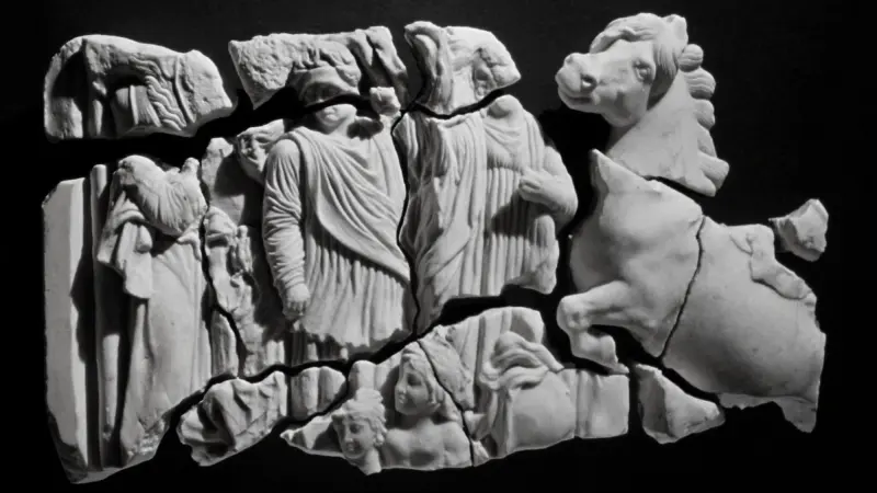 Fragmented marble frieze with robed figures and a horse on a dark ground
